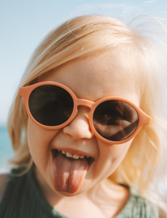 Une petite fille portant des lunettes de soleil tire la langue.