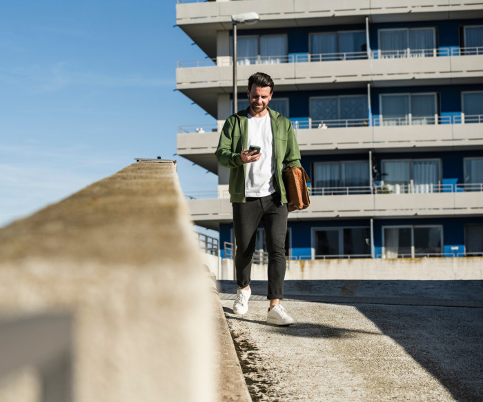 Un homme marche à l'extérieur en regardant son téléphone